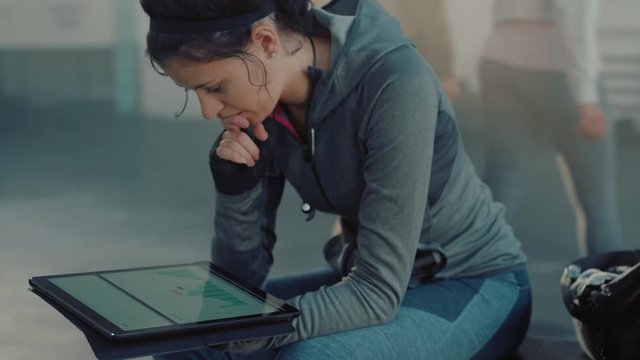 fitness woman athlete using tablet computer viewing performance results browsing charts on mobile device screen enjoying exercise goal resting in fitness gym