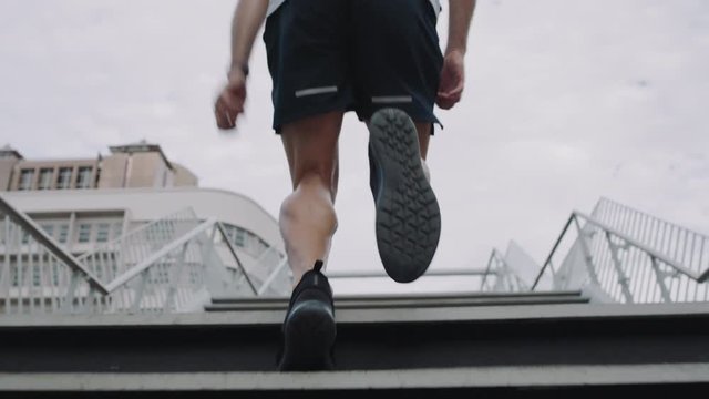 young man athlete legs running up stairs training intense cardio workout exercise male runner feet jogging on steps in urban city background