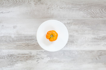 Yellow tomato on light wooden surface