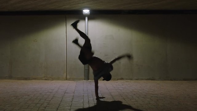 dancing man young break dancer performing modern hip hop dance moves under street light practicing spinning urban freestyle choreography in city at night