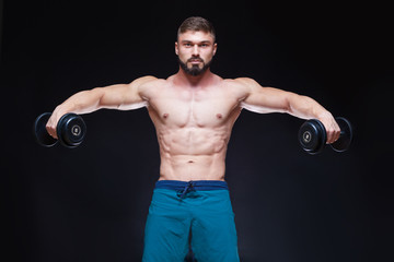 Fototapeta na wymiar Muscular bodybuilder guy doing exercises with dumbbell over black background