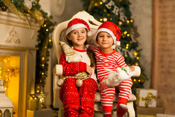 Fototapeta na wymiar Happy children sit together on a chair near the Christmas tree