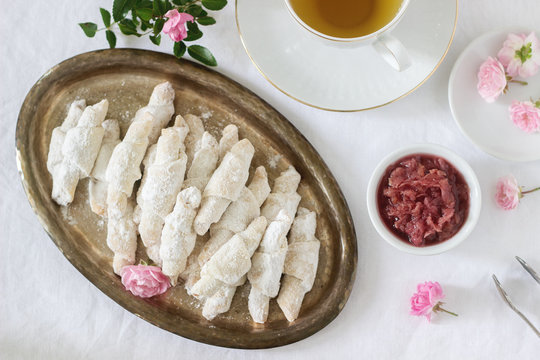 Traditional Romanian or Moldavian shortcake cookies with jam stuffing and a cup of tea on the light background.
