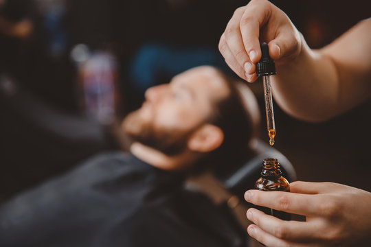 Oil for care and growth of beard, in background man.