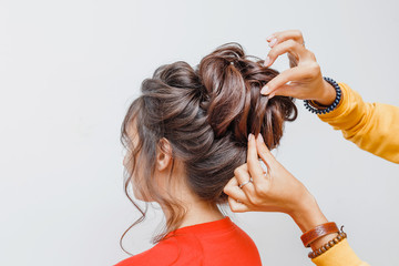 Les mains de la coiffeuse professionnelle faisant une coiffure de mariée ou de soirée avec des boucles pour son client en studio