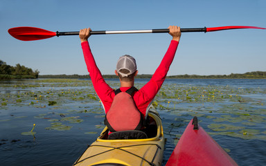 man in a kayak on a river with a raised oar