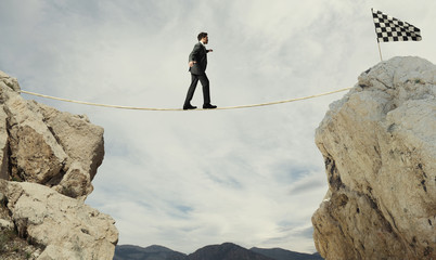 Business concept of businessman who overcome the problems reaching the flag on a rope