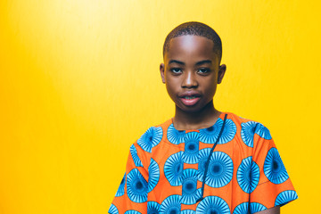 Portrait of boy standing against yellow wall