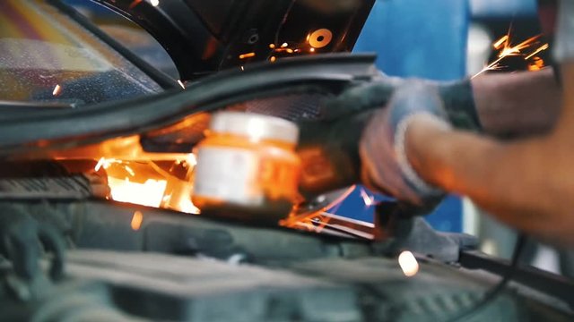 Mechanic's hands welds a part of the car with a welding machine
