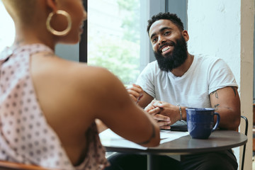 Happy couple talking with each other while sitting in cafe
