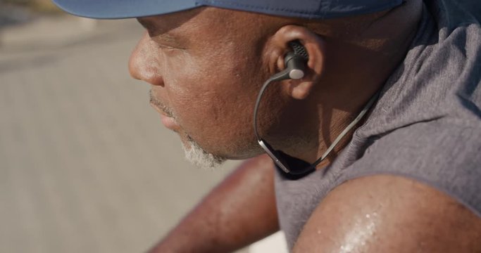 overweight runner man mature african american jogger exhausted after intense fitness workout resting on sunny beach seaside close up