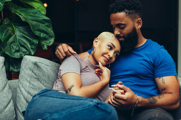 Young couple embracing each other while sitting on sofa