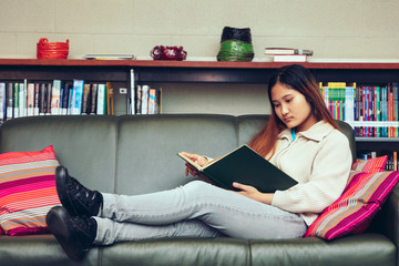 Teenage girl studying in library while sitting on the sofa
