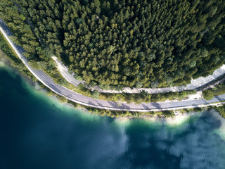 Aerial view of the road near the lake and the forest from above