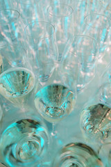 row of transparent clean wine glasses and champagne on a rack in a bar or restaurant prepared for guests of festive events. 