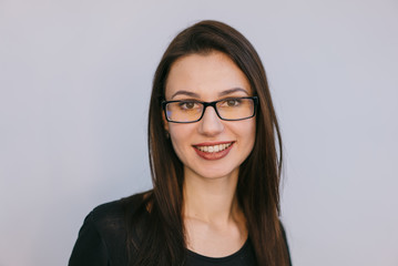 Fototapeta premium smiling young brunette with glasses on a white background. Close-up