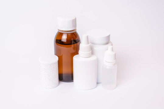 Blank empty cure remedy pattern headache medication food supplement tablets virus concept. Close up photo of white bottles with pill ear eye drops transparent brown bottle isolated on white background