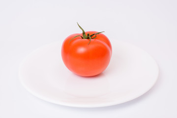 Close up front view photo of fresh with flawless ideal skin raw round tomato on round clear flat crockery isolated on white background copy-space copyspace