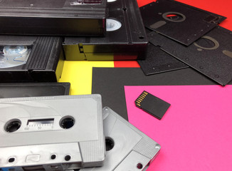 Tapes, floppy disk and memory card on colorful background. Old and modern technology.