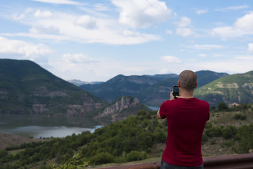 Naklejka premium Young Man Taking Pictures With Mobile Smartphone Of Mountain and Landscape