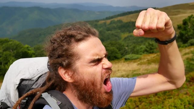 A man does selfie in the mountains. Joyous video, turn in a circle