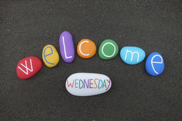 Welcome Wednesday text with multi colored stones over black volcanic sand
