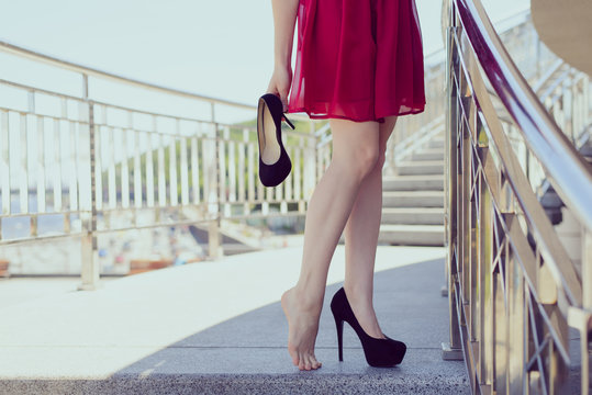Relief new shoes feeling discomfort too small size girlish feminine problem concept. Side profile front close up lifestyle view photo of beautiful pretty happy student holding black high heels in hand