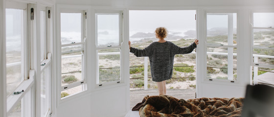 Rear view of a woman looking out of a beach house
