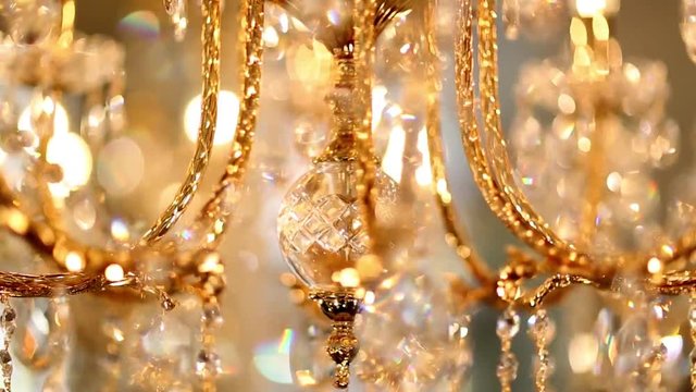 A crystal chandelier with crystals shimmers with bright lights and rotates. The ceiling light rotates and is brightly reflected in the mirror. Volumetric golden lamp with crystals rotates smoothly.