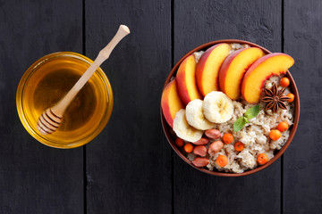 Oatmeal and honey on dark wooden boards. Cooked oatmeal with fruit and honey for breakfast. Healthy...