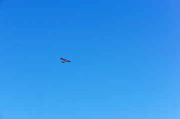 A small aircraft soars in the blue sky. Glider in the sky.