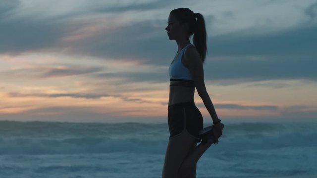 young woman runner athlete stretching warm up active female running exercise on beach early morning seaside at sunrise