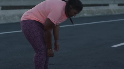 overweight african american woman resting after intense running exercise training cardio weight loss workout in urban city at sunrise exhausted black female runner