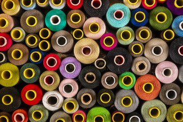 Bright composition of wooden and plastic sewing spools with colorful vibrant threads from above