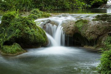 Small waterfall flowing on rock in woods in long exposure