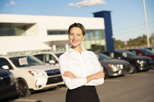Young woman car rental in front of garage with cars on the background