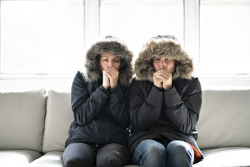 Couple have cold on the sofa at home with winter coat - obrazy, fototapety, plakaty