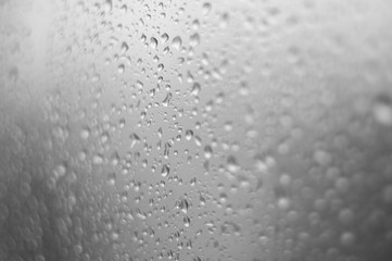 raindrops on window glass on background of cloudy sky