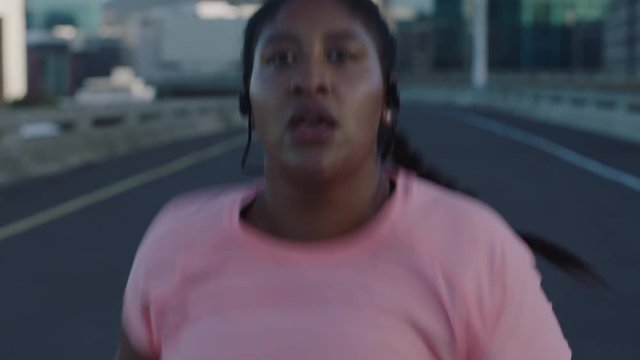 overweight woman runner exercising running weight loss challenge resting exhausted looking serious at camera in urban city sunset