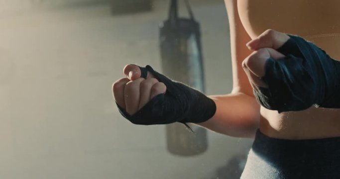 fitness woman kickboxer wrapping hands preparing for exercise workout female boxer athlete using hand wrap strong sportswoman fighter enjoying healthy lifestyle close up slow motion