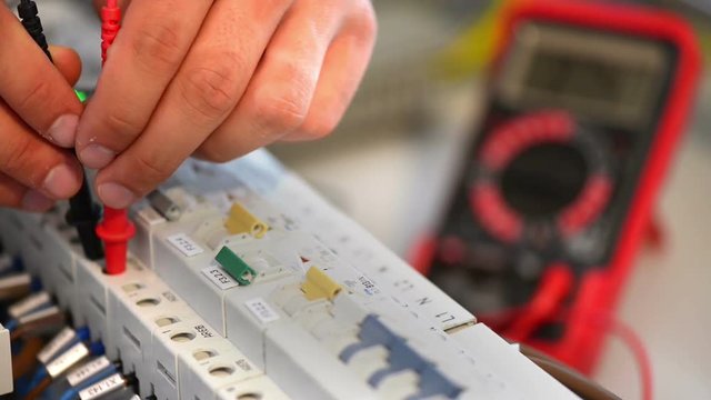 Electrician testing an electric smart panel fuse box, using a multimeter tester