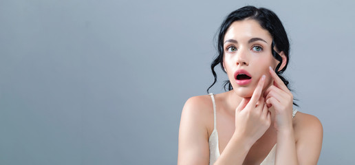 Young woman with skin blemish theme on a gray background