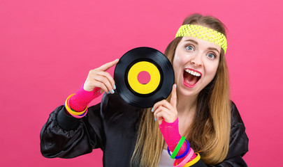 Woman in 1980's fashion holding a record on a pink background