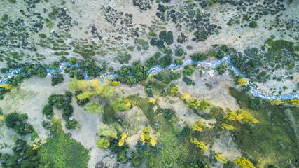 An aerial view at "Yerba Loca" Nature Reserve, the river flows through the Andes Valleys in between the colorful yellow and green trees during Autumn Season at Central Andes, Santiago de Chile