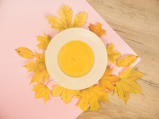Roasted pumpkin and carrot soup with cream and seeds on white wooden background. Dietary vegetarian pupmkin cream soup puree, on brown wooden table, top view, close up. Hot autumn soup for vegan.