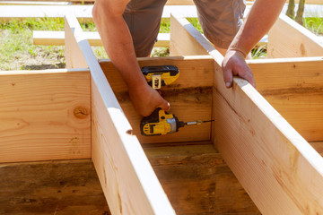 Full length carpenter drilling wood at construction site