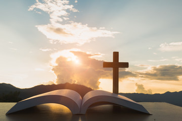 open Bible, script in blur with focus on palm cross,on sunrise background, Crucifix, Symbol of Faith. - obrazy, fototapety, plakaty