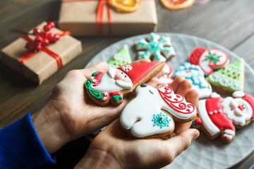 Gingerbread cookies for christmas, new year in kids hands on the wooden table. Festive, sweet pastry, delicious biscuits. Home celebration, decoration concept