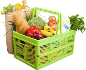 Shopping cart filled with various groceries on white