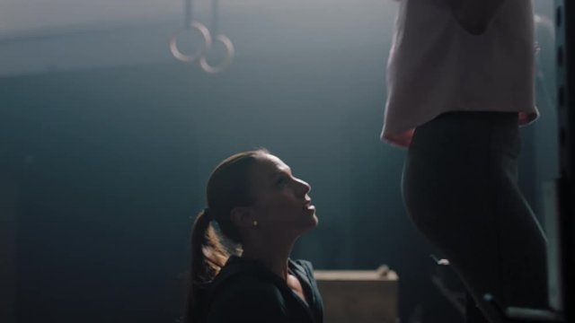 healthy woman training pull ups exercise enjoying intense fitness workout personal trainer helping diverse friends high five in gym